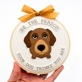 Handmade fabric hoop art piece with dog gazing upwards, surrounded by wording that says "Be the person your dog thinks you are".