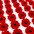 Red fabric poppy flowers with black bead centers, arranged closely together on a white background.