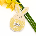Yellow bunny-shaped Easter decoration with 'NOAH' tag on a white background